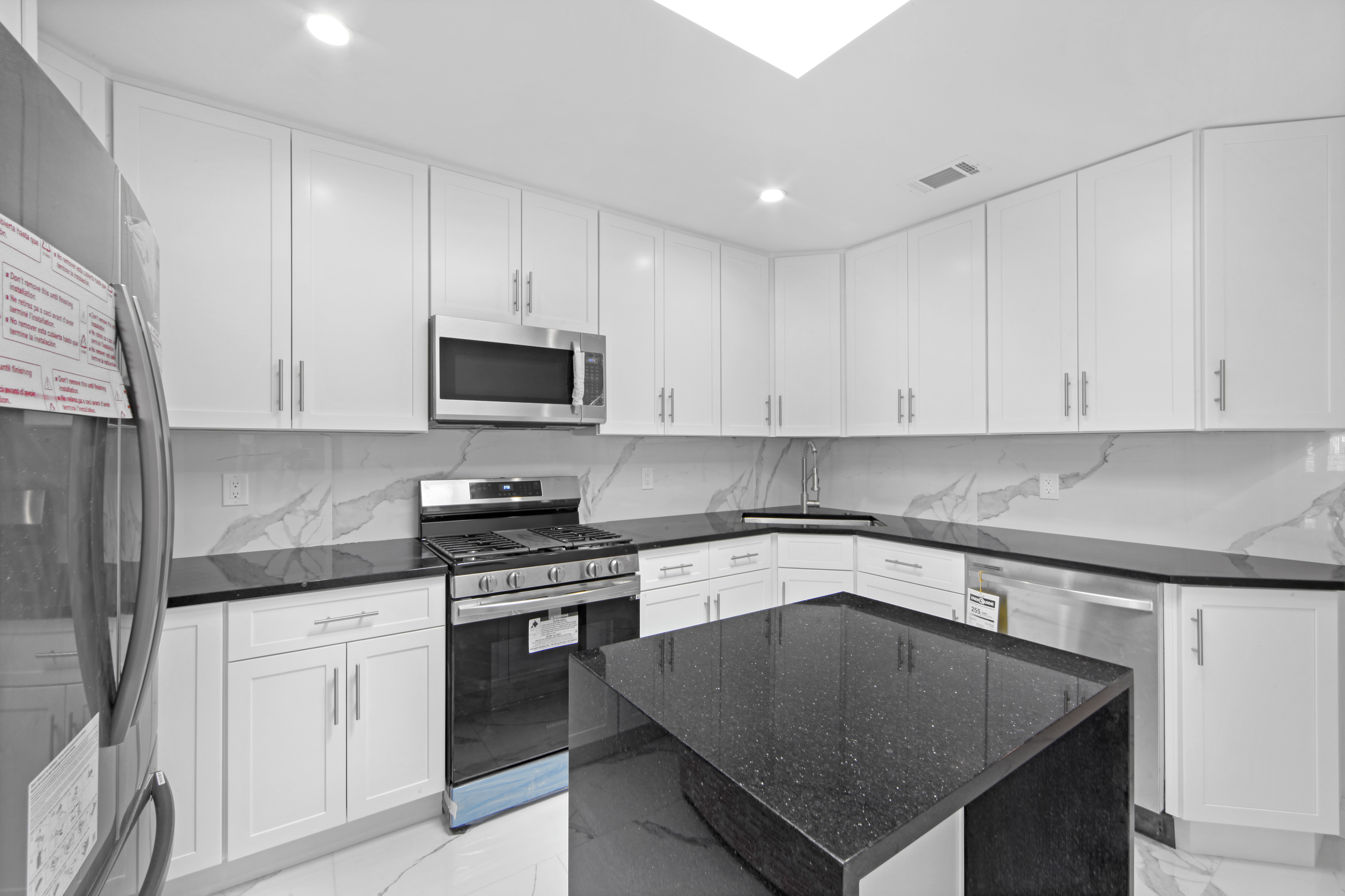 2345 East 1st Street, Unit 2 Brooklyn, NY 11223 - Photo 4 of 10 a kitchen with granite countertop white cabinets sink and stainless steel appliances