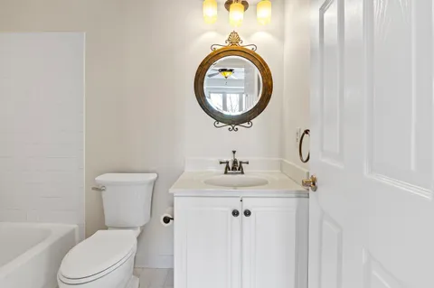 a bathroom with a toilet sink vanity and mirror