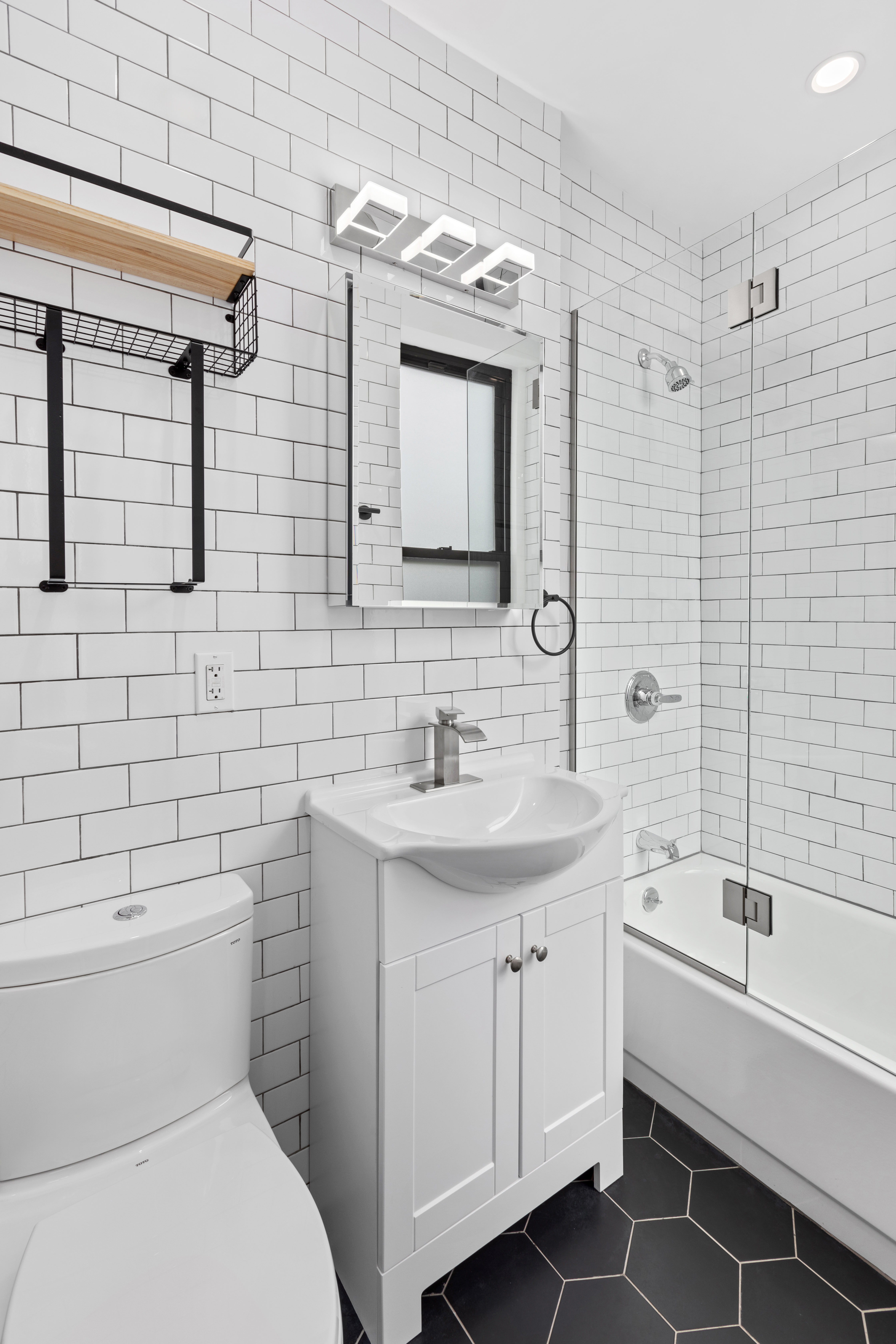 64 MacDougal Street, Unit 7 Manhattan, NY 10012 - Photo 5 of 5 a bathroom with a toilet a sink a mirror a bathtub and shower