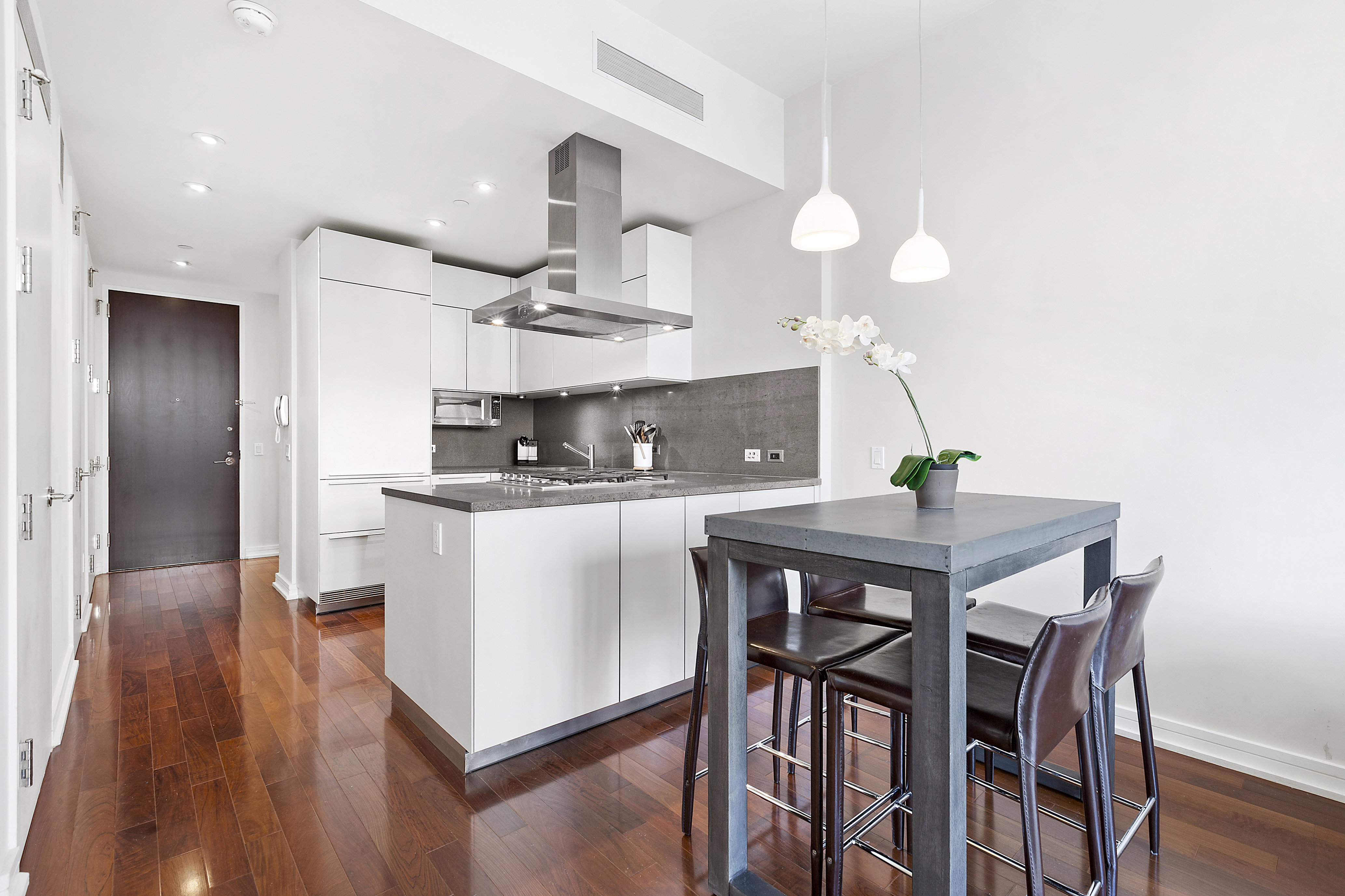 101 Warren Street, Unit 840 Manhattan, NY 10007 - Photo 2 of 16 a kitchen with stainless steel appliances kitchen island hardwood floor and wooden cabinets
