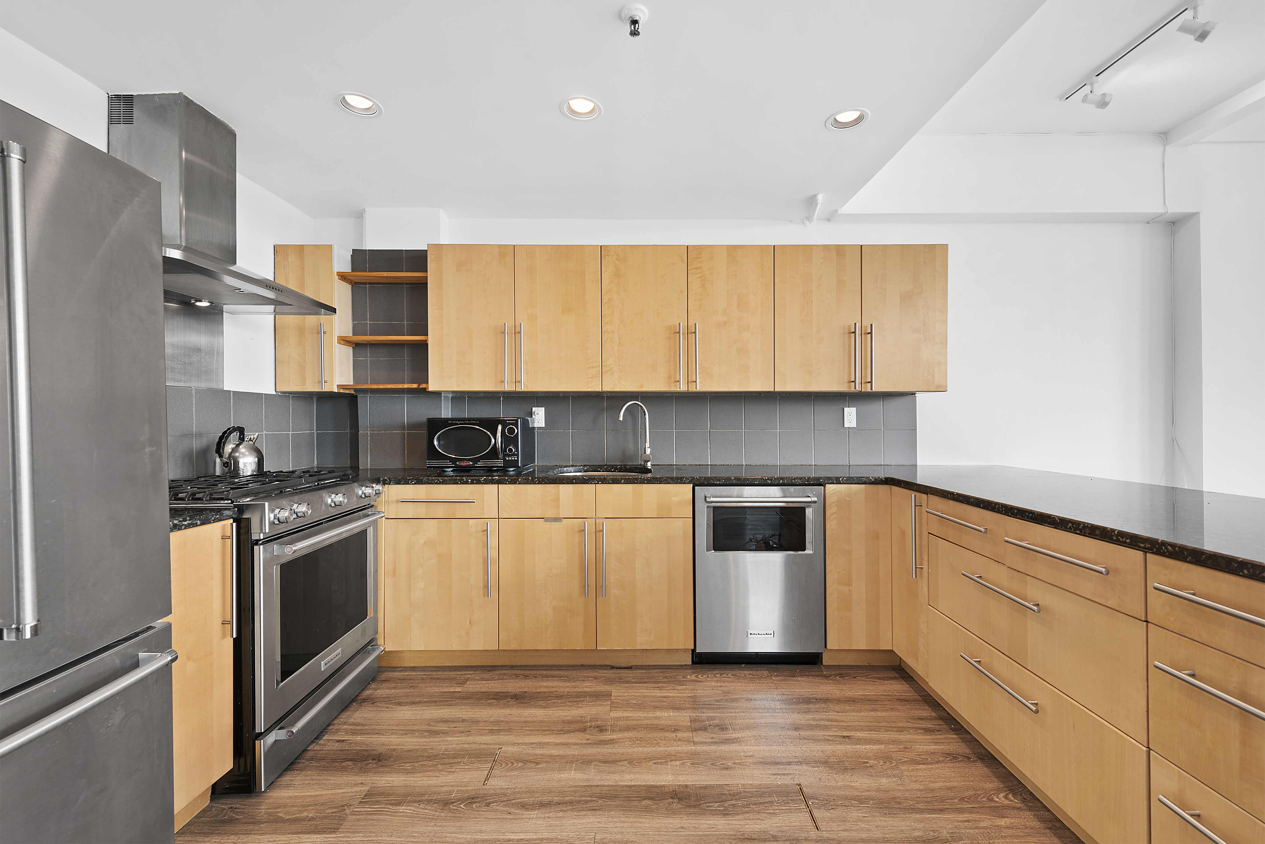 40 West 17th Street, Unit PH12C Manhattan, NY 10011 - Photo 4 of 11 a kitchen with stainless steel appliances granite countertop a stove a sink and a refrigerator