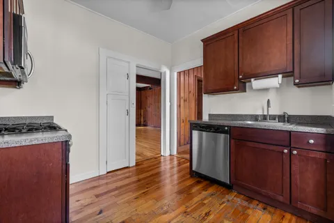 a kitchen with stainless steel appliances granite countertop a stove top oven a sink and dishwasher with wooden floor