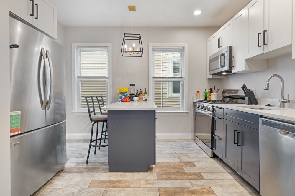 24 Buttonwood Street Boston, MA 02125 - Photo 33 of 43 a kitchen with stainless steel appliances granite countertop a refrigerator sink and wooden cabinets