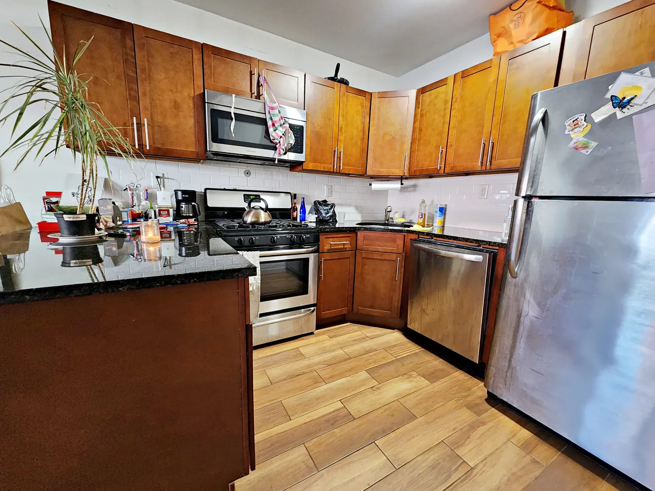 a kitchen with stainless steel appliances granite countertop a refrigerator a stove top oven a sink dishwasher and wooden cabinets