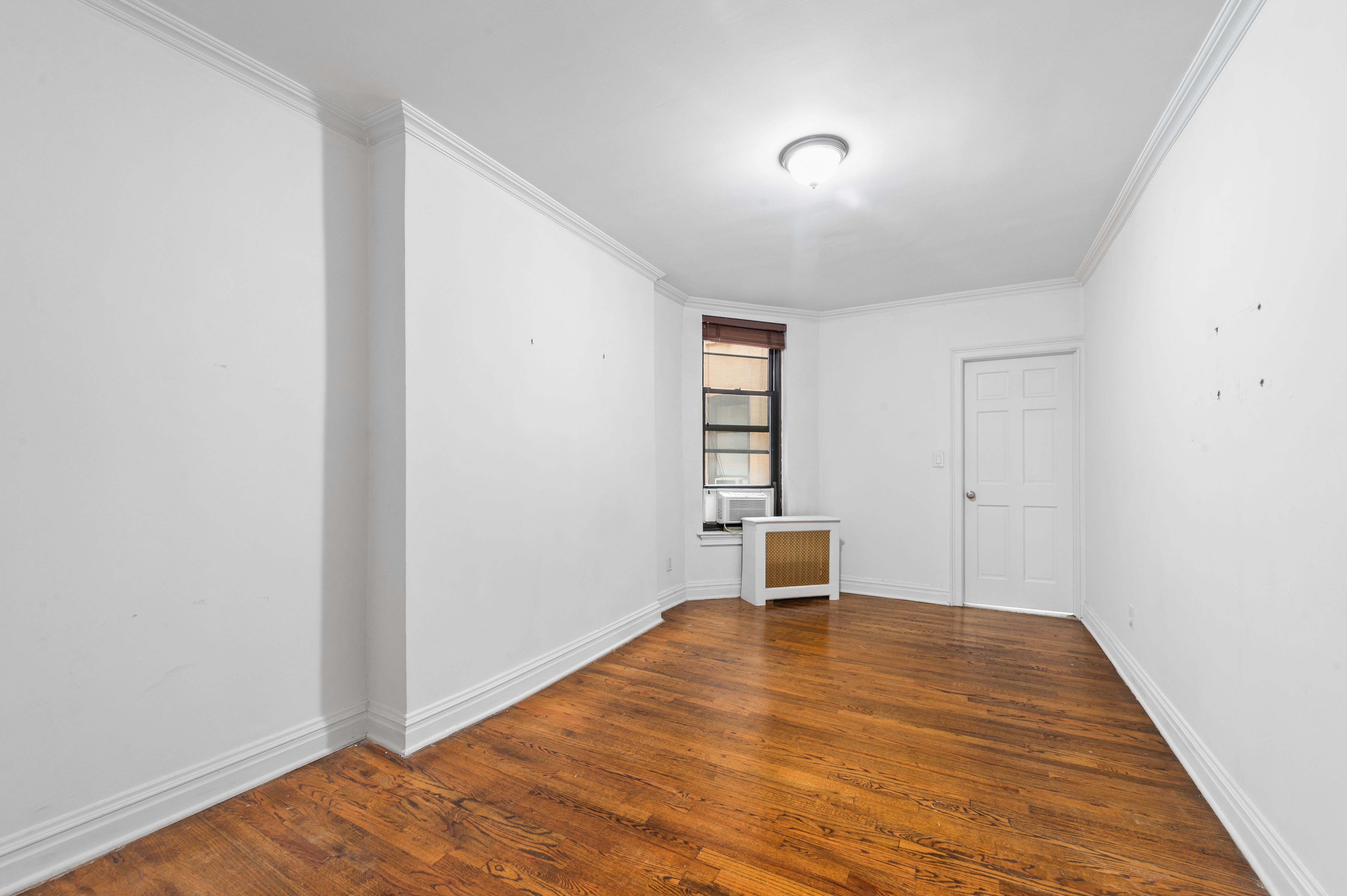 142 Sullivan Street, Unit 21 Manhattan, NY 10012 - Photo 7 of 8 an empty room with wooden floor cabinet and windows