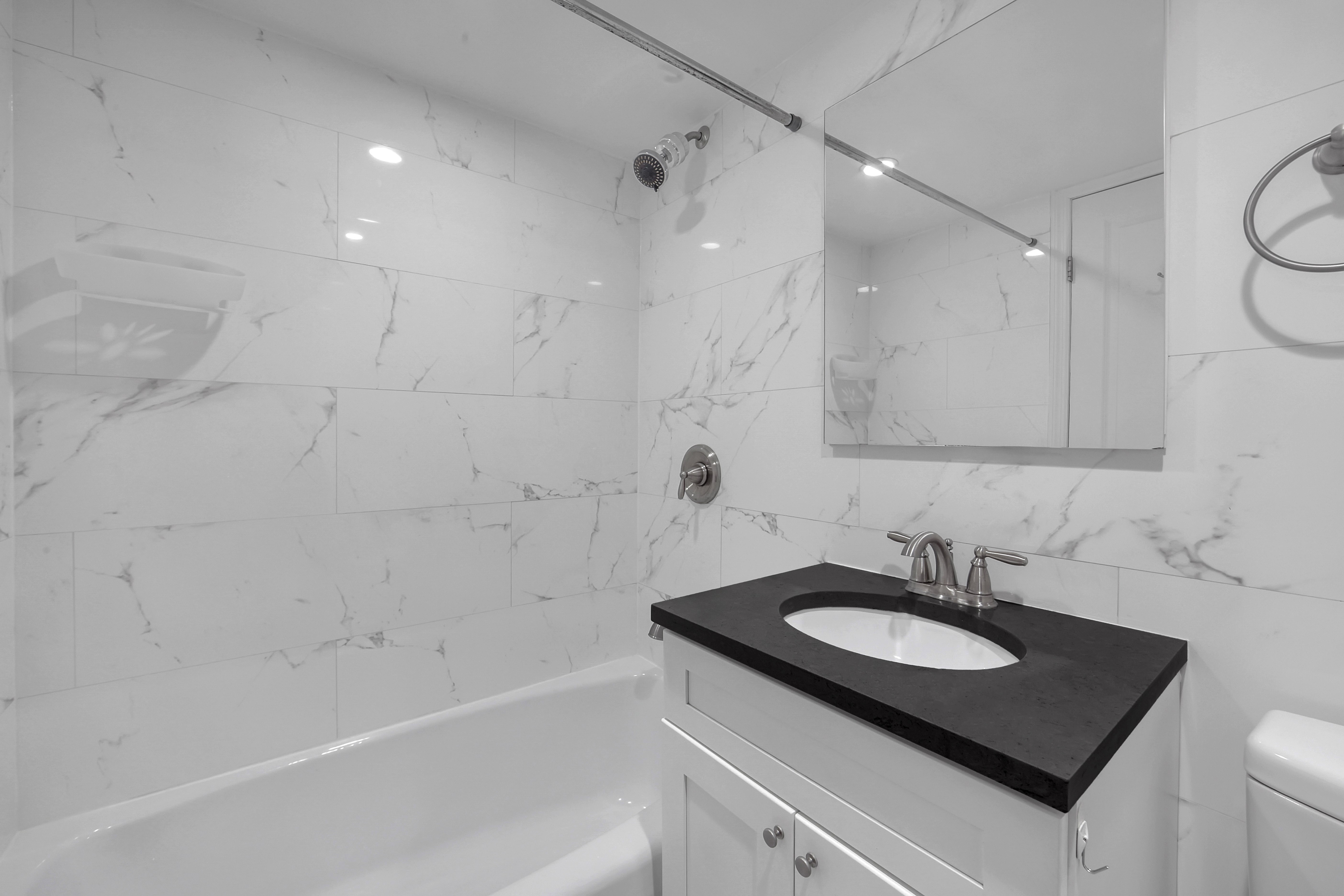 520 East 81st Street, Unit 14C Manhattan, NY 10028 - Photo 10 of 13 a bathroom with a sink vanity granite tub shower and a mirror