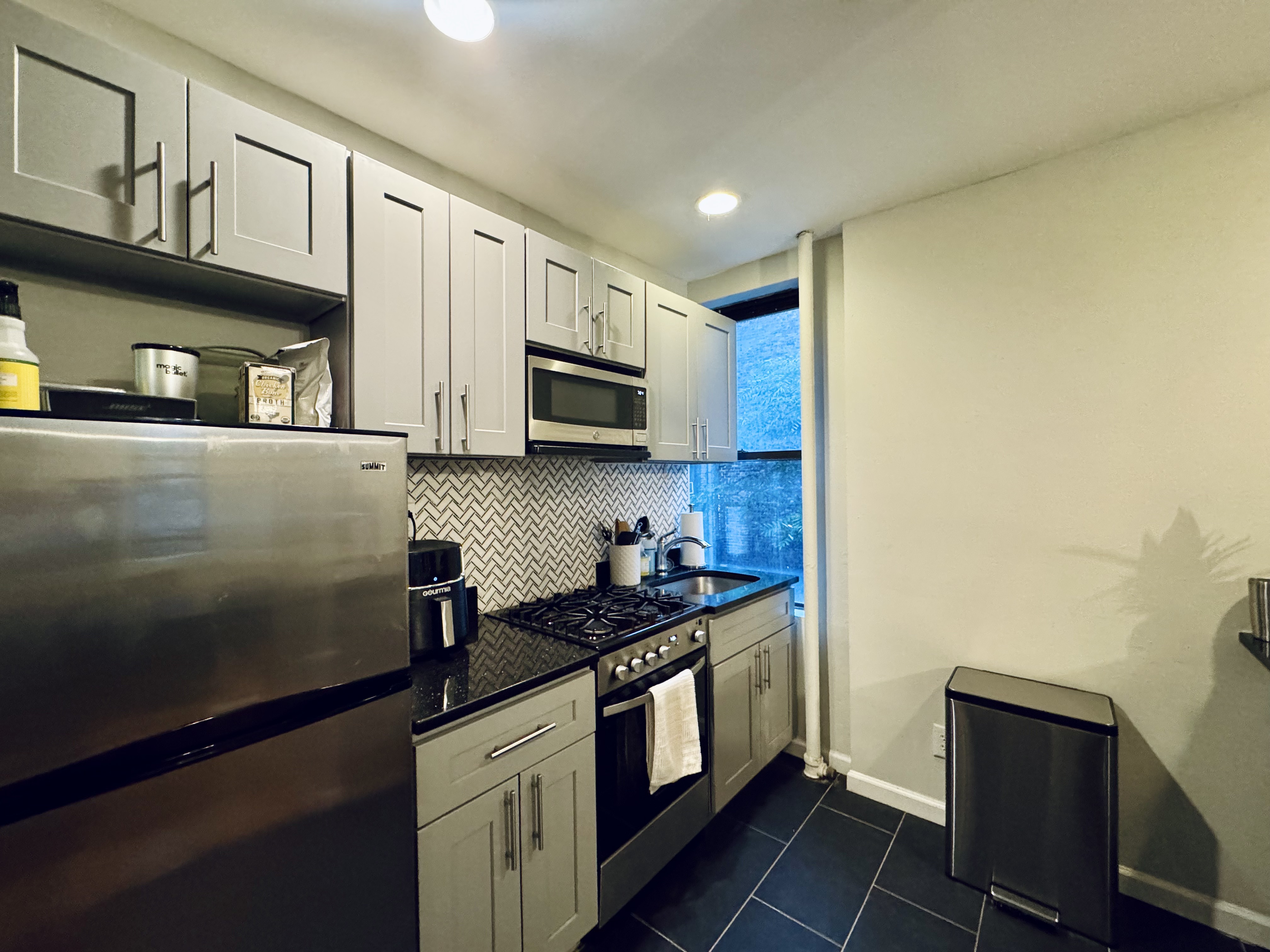 210 Thompson Street, Unit 4DN Manhattan, NY 10012 - Photo 3 of 10 a kitchen with stainless steel appliances a refrigerator a stove a sink a stove and cabinets
