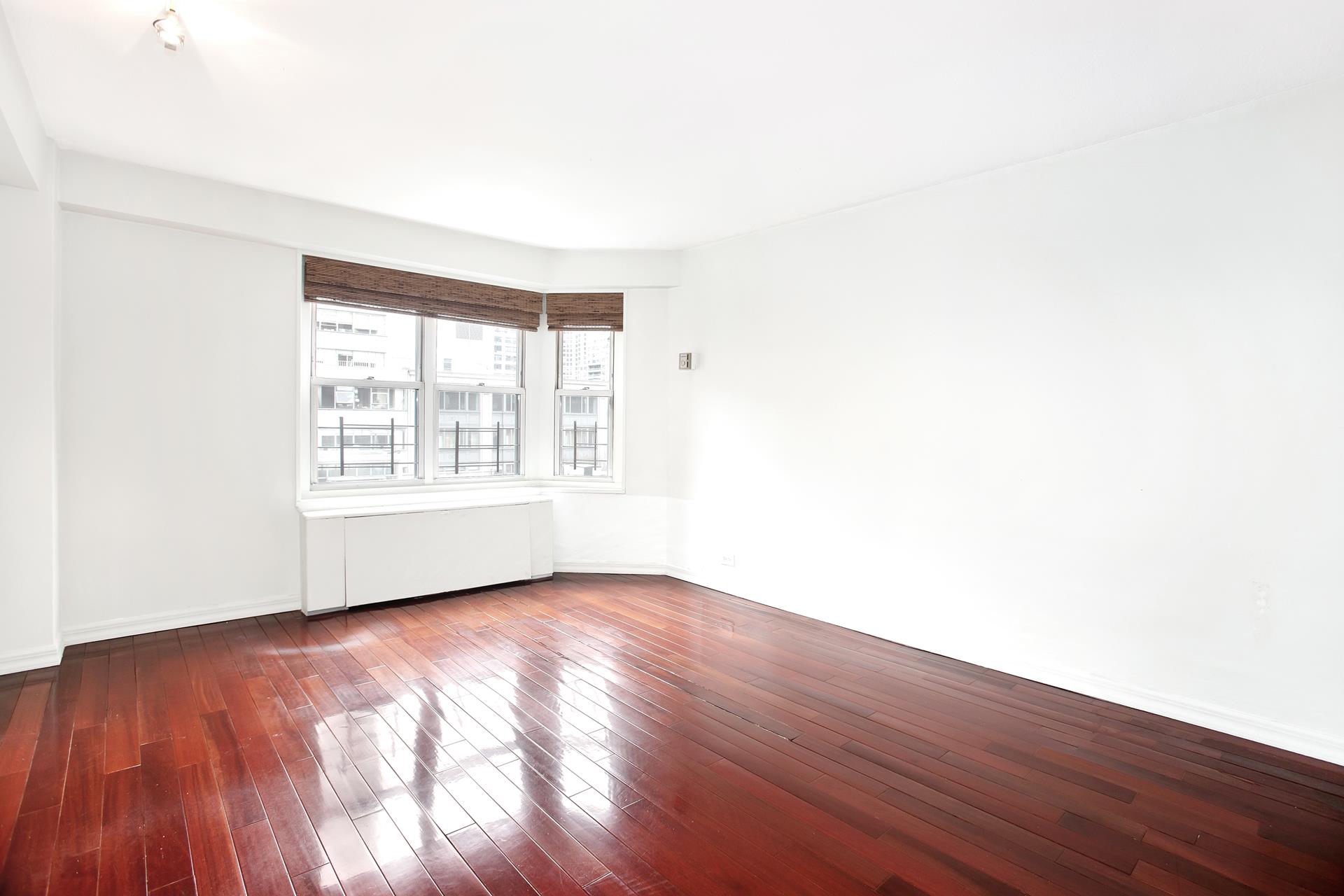 220 East 60th Street, Unit 7CD Manhattan, NY 10022 - Photo 9 of 11 an empty room with wooden floor and windows