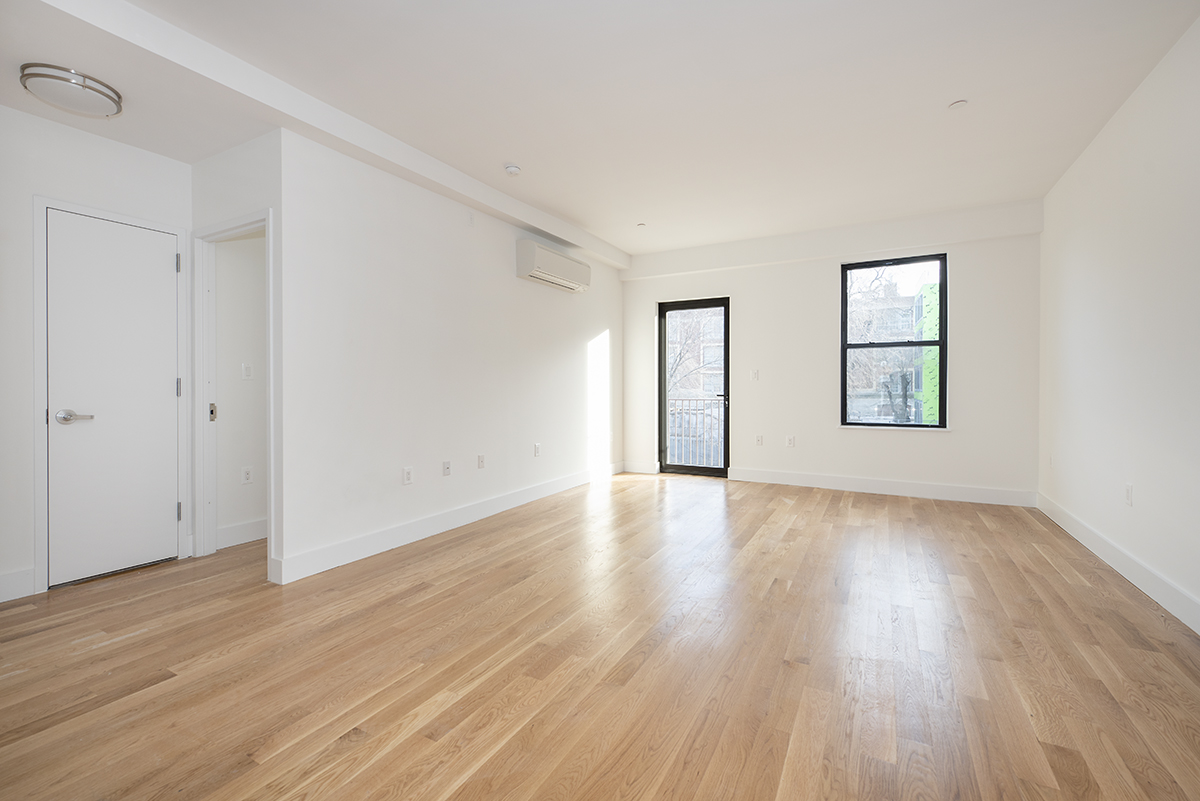 216 Boerum Street, Unit 3B Brooklyn, NY 11206 - Photo 2 of 10 an empty room with wooden floor and windows