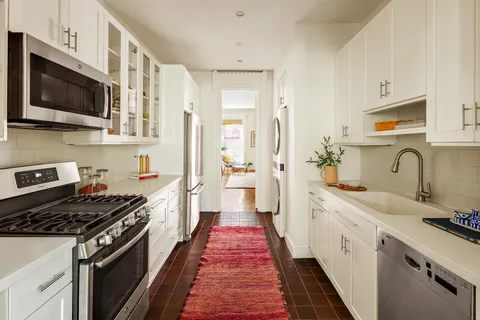 a kitchen with stainless steel appliances a sink dishwasher refrigerator stove and microwave with wooden floor