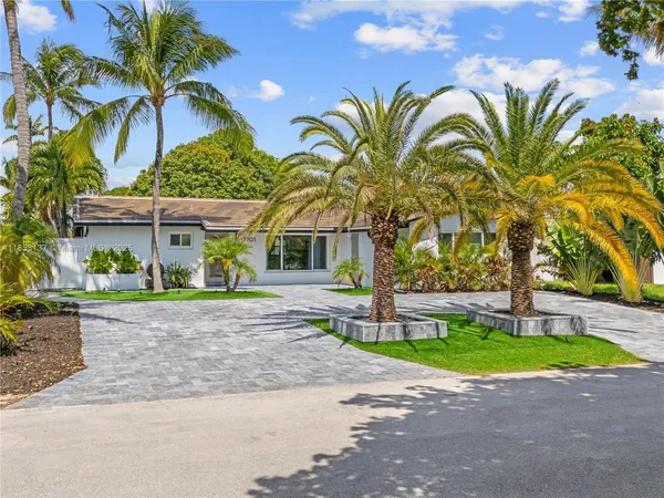 a view of a house with a small yard and palm trees