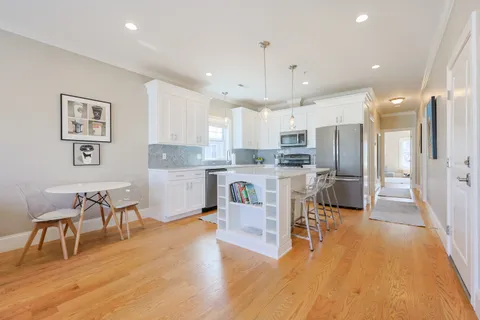 a kitchen with stainless steel appliances kitchen island granite countertop wooden floors and cabinets