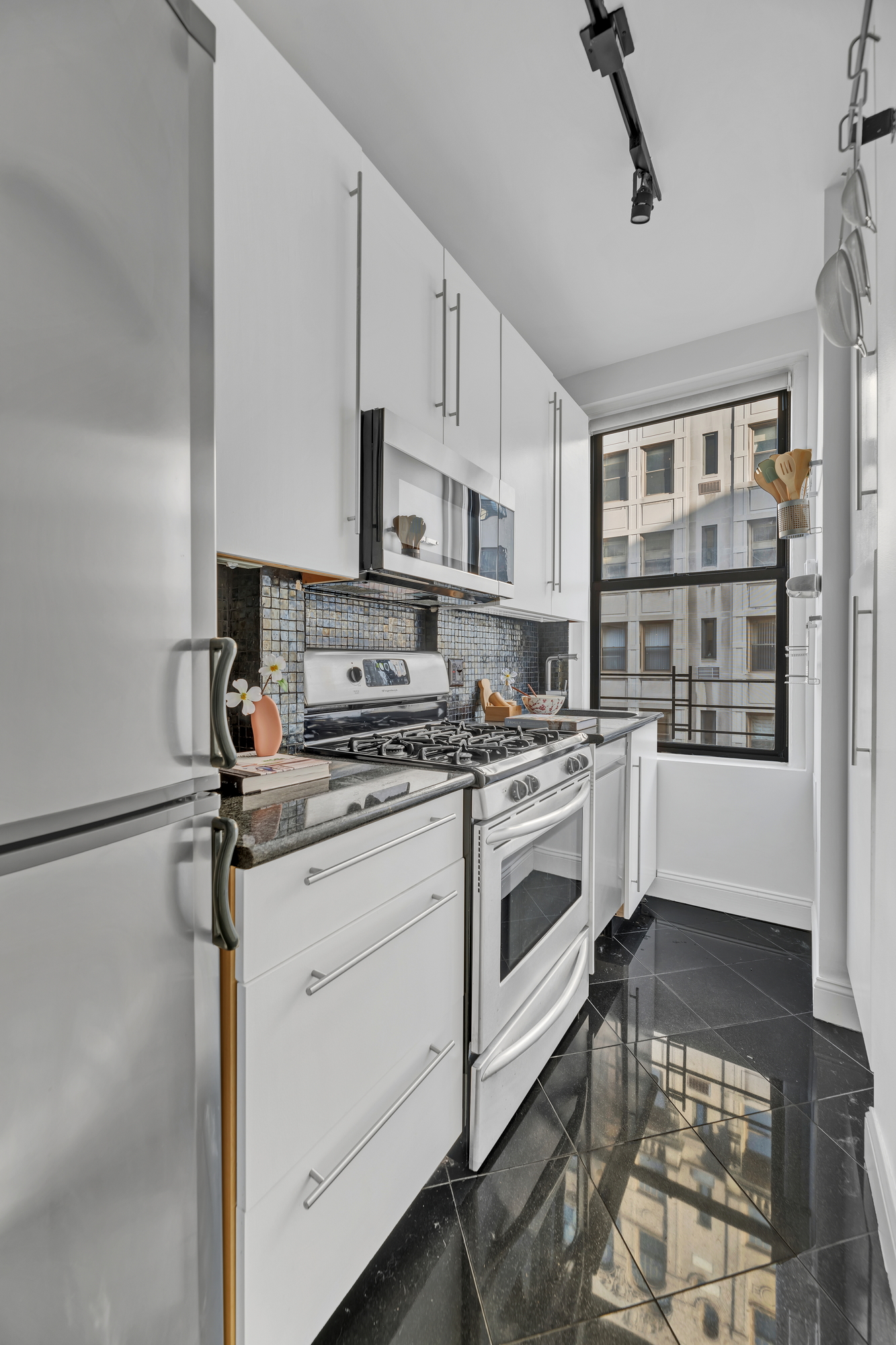 599 West End Avenue, Unit 7BC Manhattan, NY 10024 - Photo 5 of 11 a kitchen with stainless steel appliances a stove a sink and white cabinets