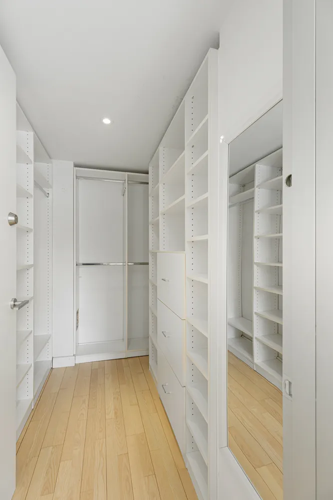 a view of an empty room with wooden floor and closet