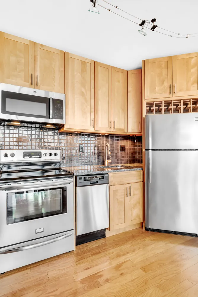 a kitchen with granite countertop white cabinets and stainless steel appliances