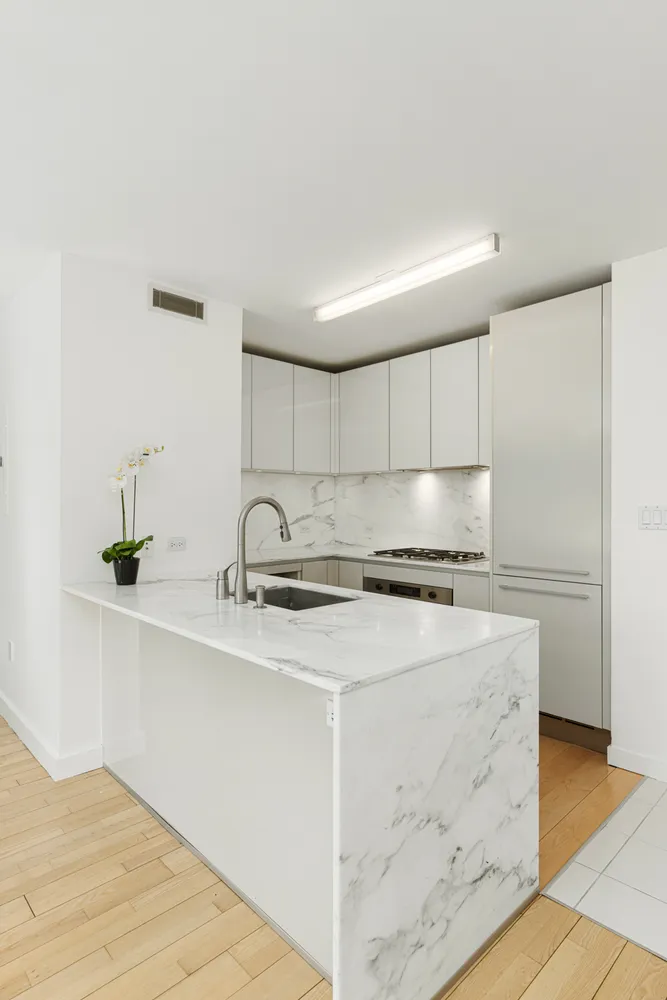 a kitchen with stainless steel appliances granite countertop a sink dishwasher a stove and a refrigerator with wooden floor