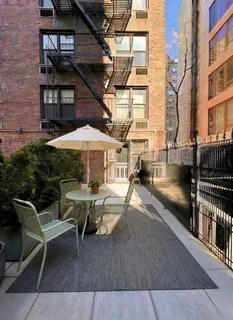 a view of a roof deck with table and chairs under an umbrella