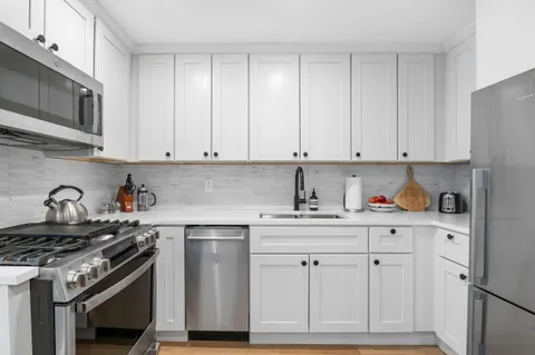a kitchen with granite countertop white cabinets and stainless steel appliances