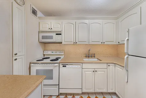 a kitchen with granite countertop white cabinets and refrigerator
