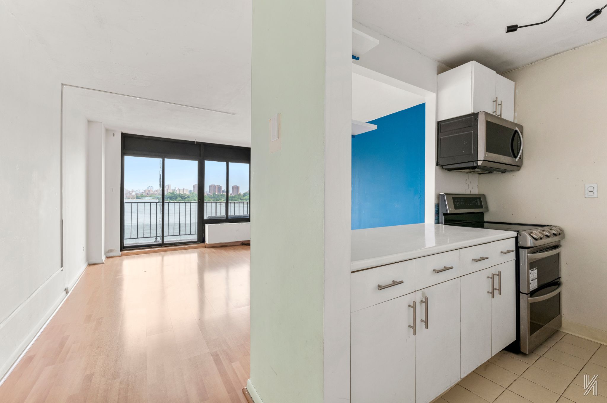 25-40 Shore Boulevard, Unit 4R Queens, NY 11102 - Photo 3 of 11 a kitchen with stainless steel appliances white cabinets and wooden floors