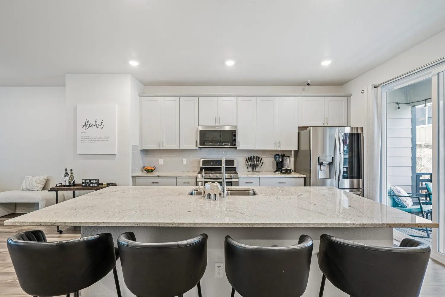 a kitchen with stainless steel appliances granite countertop a sink a stove a refrigerator and white cabinets