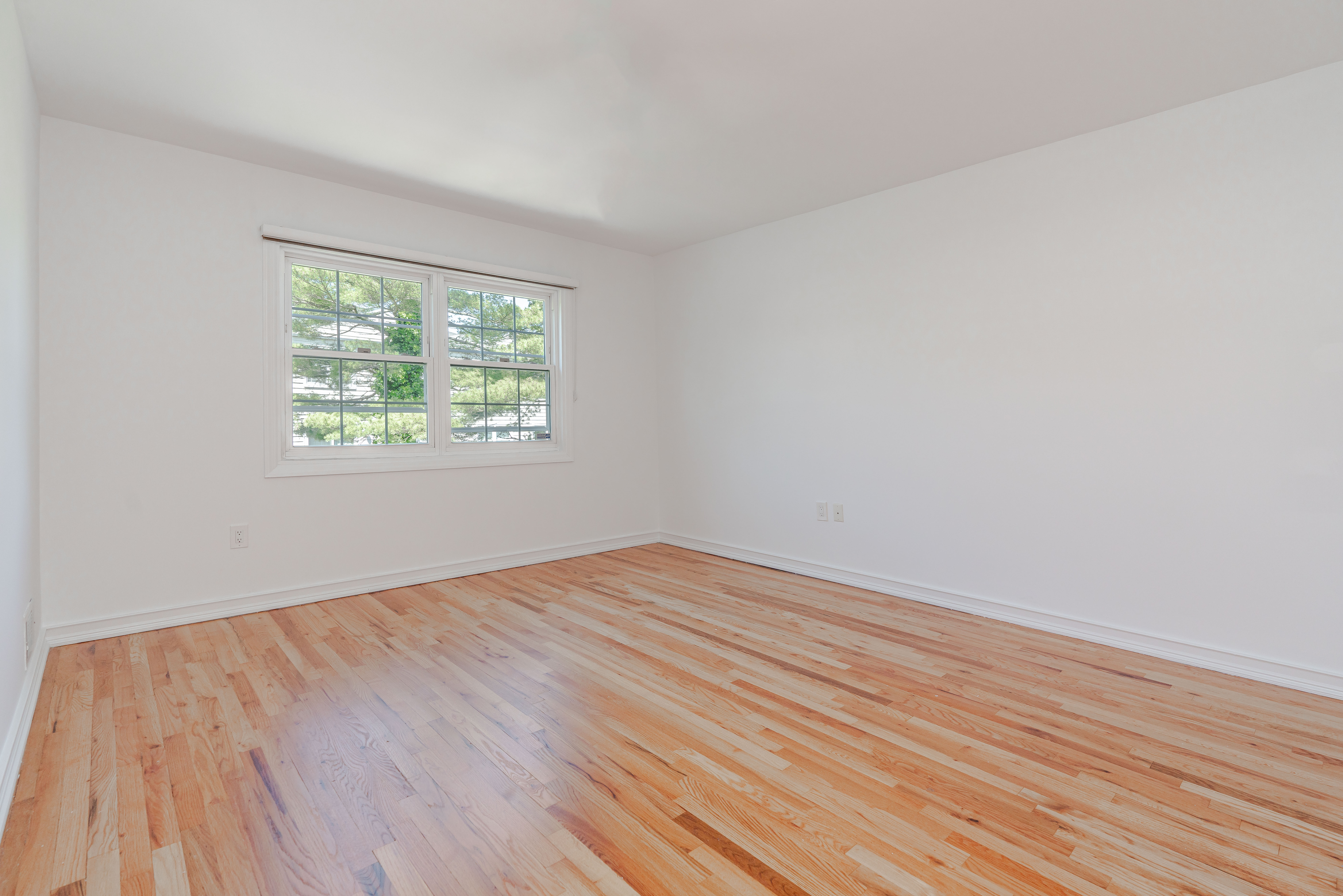 15-80 209th Street, Unit 2 Queens, NY 11360 - Photo 9 of 11 an empty room with wooden floor and windows