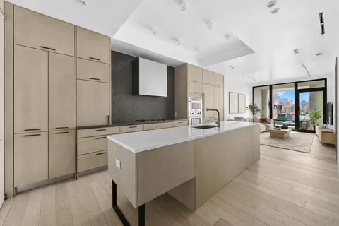 a living room with stainless steel appliances furniture refrigerator and a kitchen view