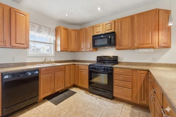 a kitchen with stainless steel appliances granite countertop a stove a sink dishwasher and a microwave oven with wooden cabinets