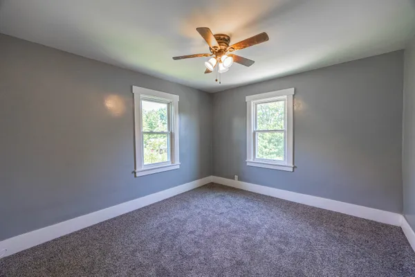 an empty room with closet and a chandelier fan
