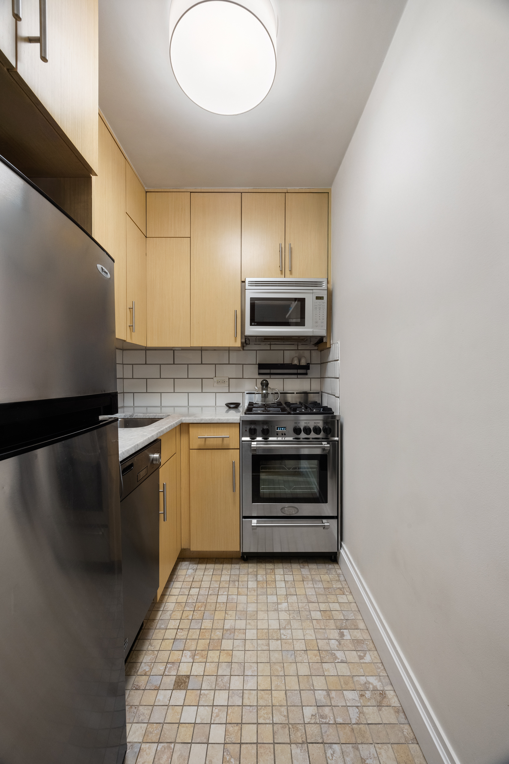 175 West 12th Street, Unit 4L Manhattan, NY 10011 - Photo 6 of 11 a kitchen with a refrigerator and a stove top oven