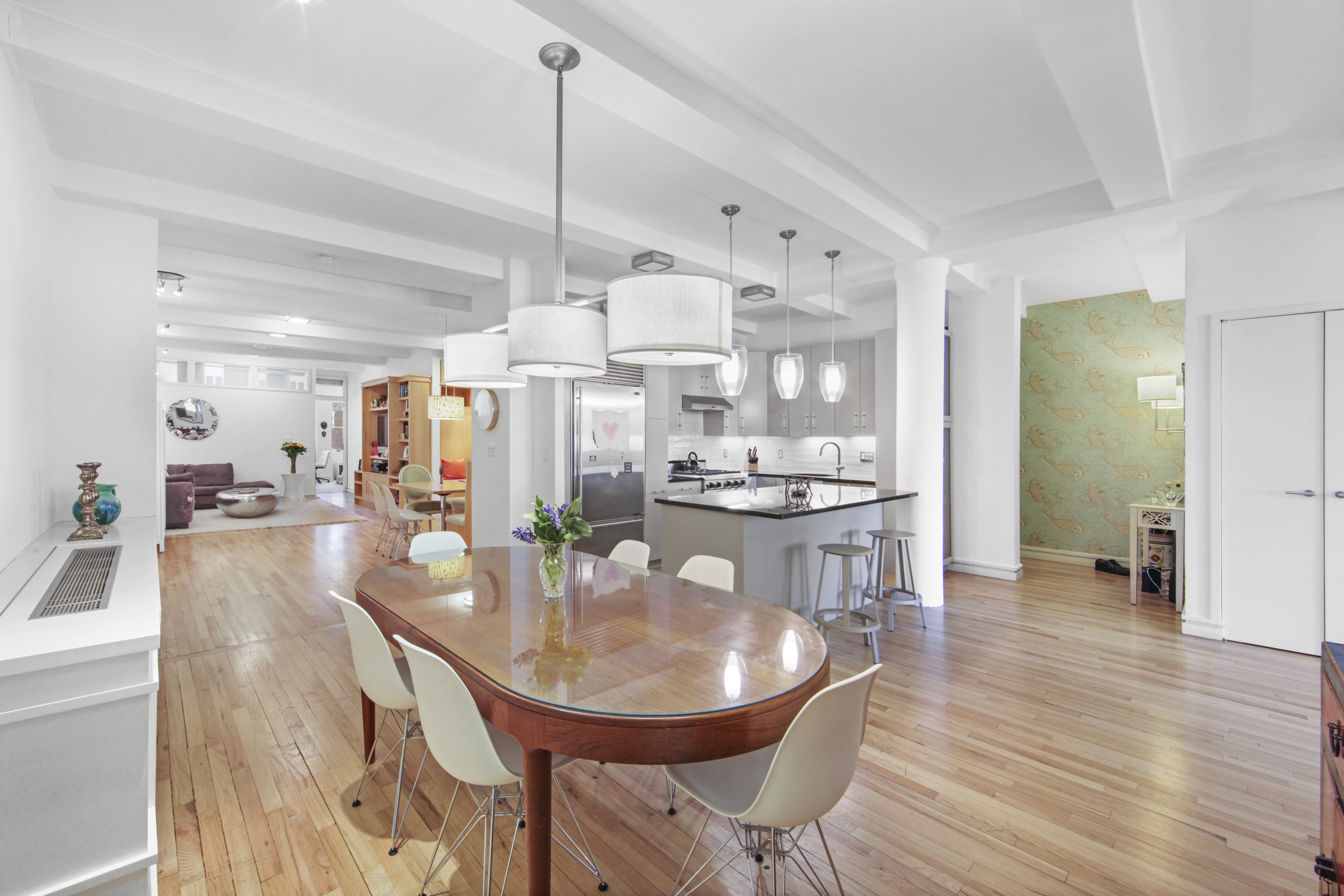 18 East 12th Street, Unit 7BC Manhattan, NY 10003 - Photo 10 of 26 a kitchen with stainless steel appliances kitchen island granite countertop a table chairs and a refrigerator