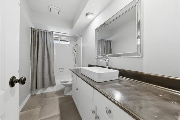 a bathroom with a granite countertop sink a toilet a mirror and shower