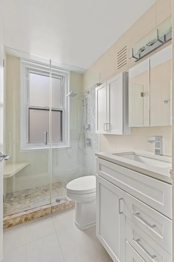 a bathroom with a granite countertop sink mirror vanity and toilet