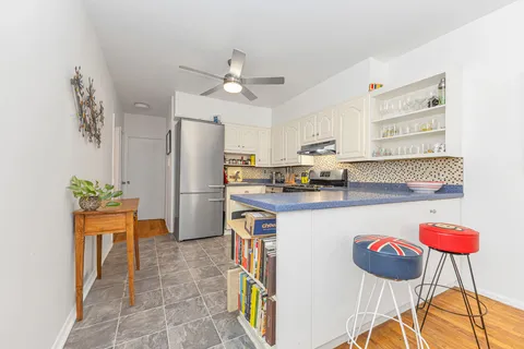 a kitchen with stainless steel appliances granite countertop a refrigerator a stove a sink a dining table and chairs with wooden floor