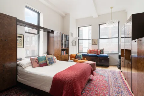 a bedroom with furniture a flat screen tv and a large window
