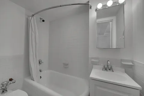 a bathroom with a white bath tub sitting next to a white sink and vanity