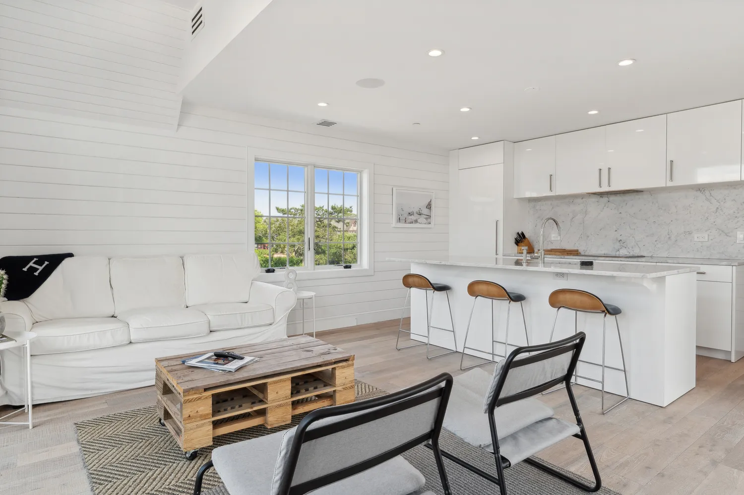 a kitchen with stainless steel appliances granite countertop a stove a sink a refrigerator and white cabinets with wooden floor