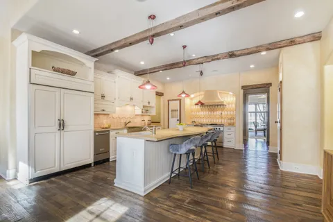 a kitchen with stainless steel appliances granite countertop a refrigerator a sink dishwasher and white cabinets with wooden floor