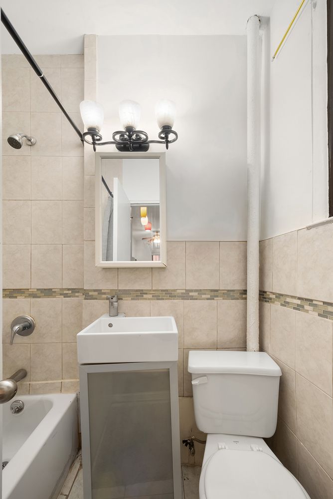 430 East 85th Street, Unit 1B Manhattan, NY 10028 - Photo 5 of 8 a bathroom with a toilet sink and mirror