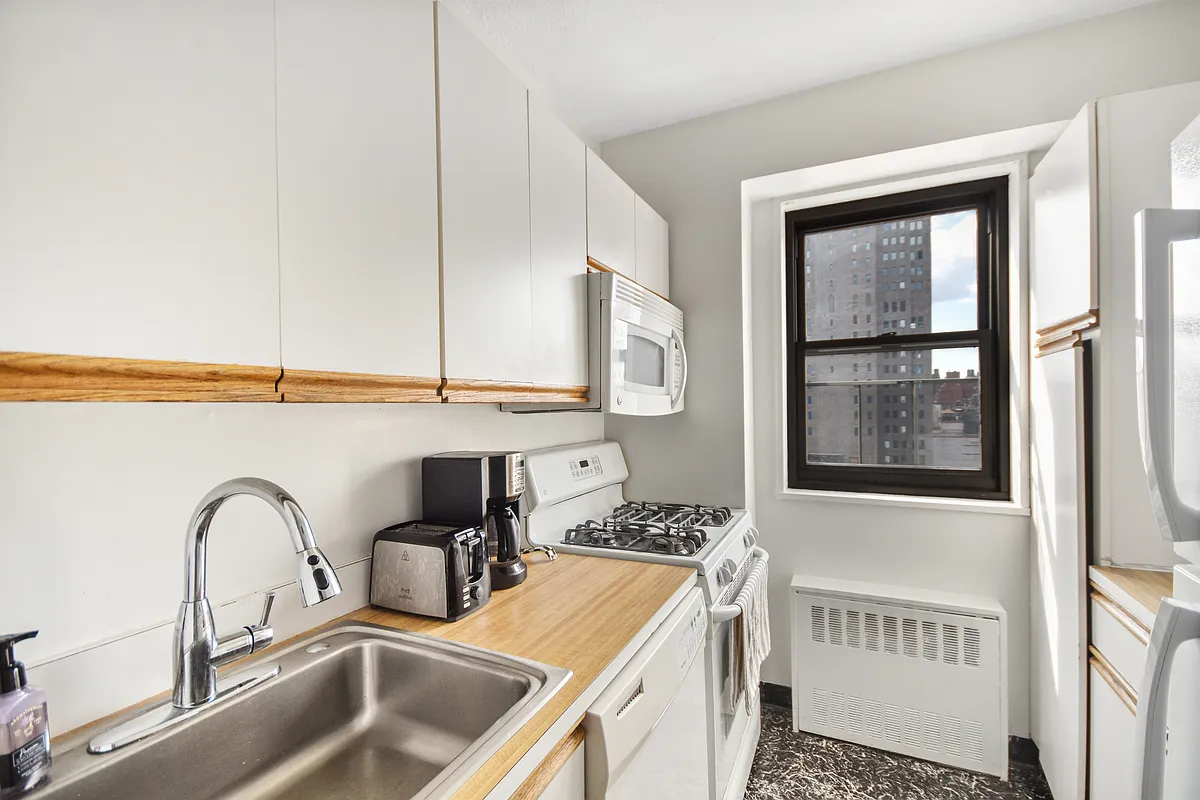 345 East 80th Street, Unit 17J Manhattan, NY 10075 - Photo 6 of 8 a kitchen with a refrigerator a sink and cabinets