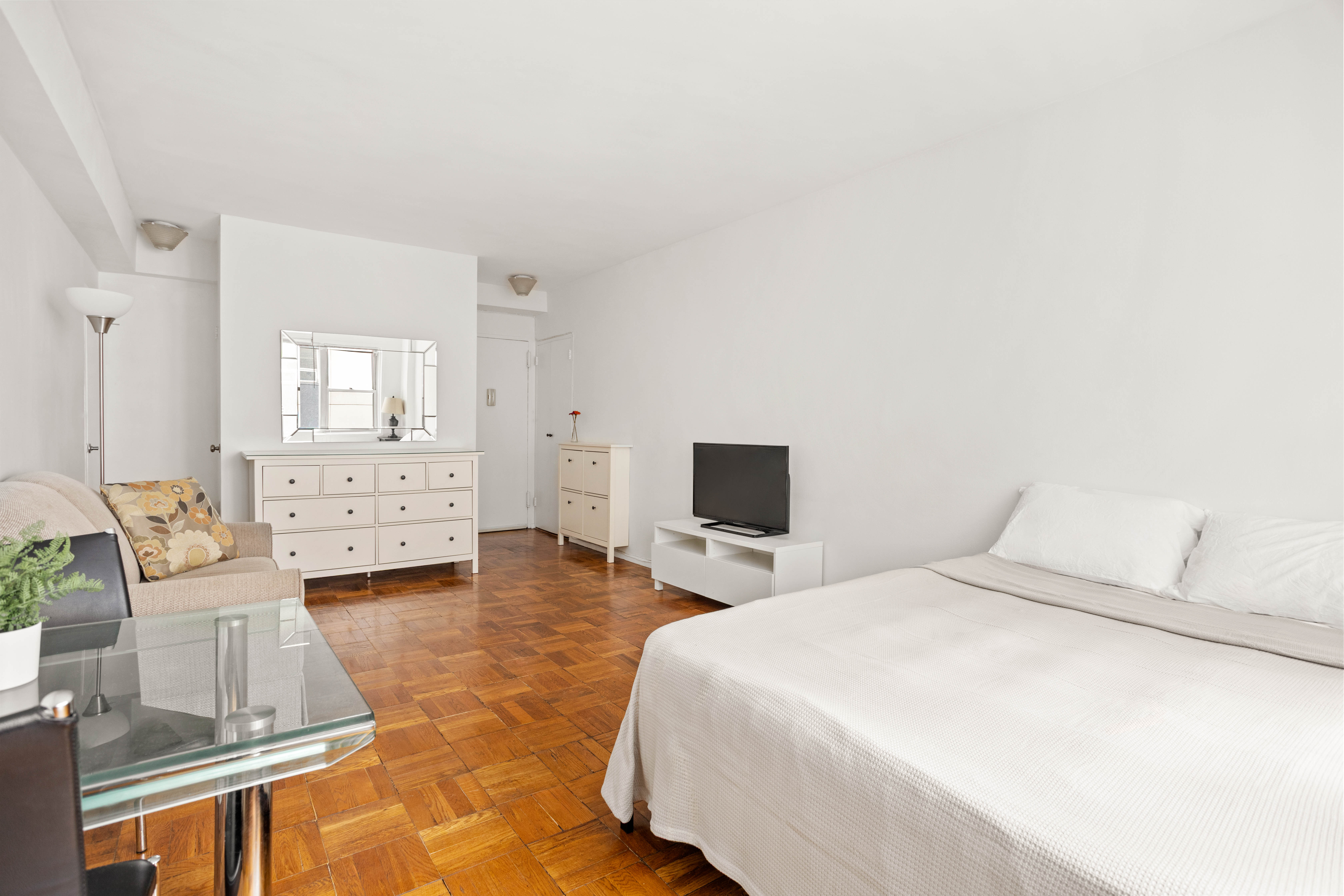 310 East 49th Street, Unit 7B Manhattan, NY 10017 - Photo 2 of 10 a bedroom with a bed a couch and dresser