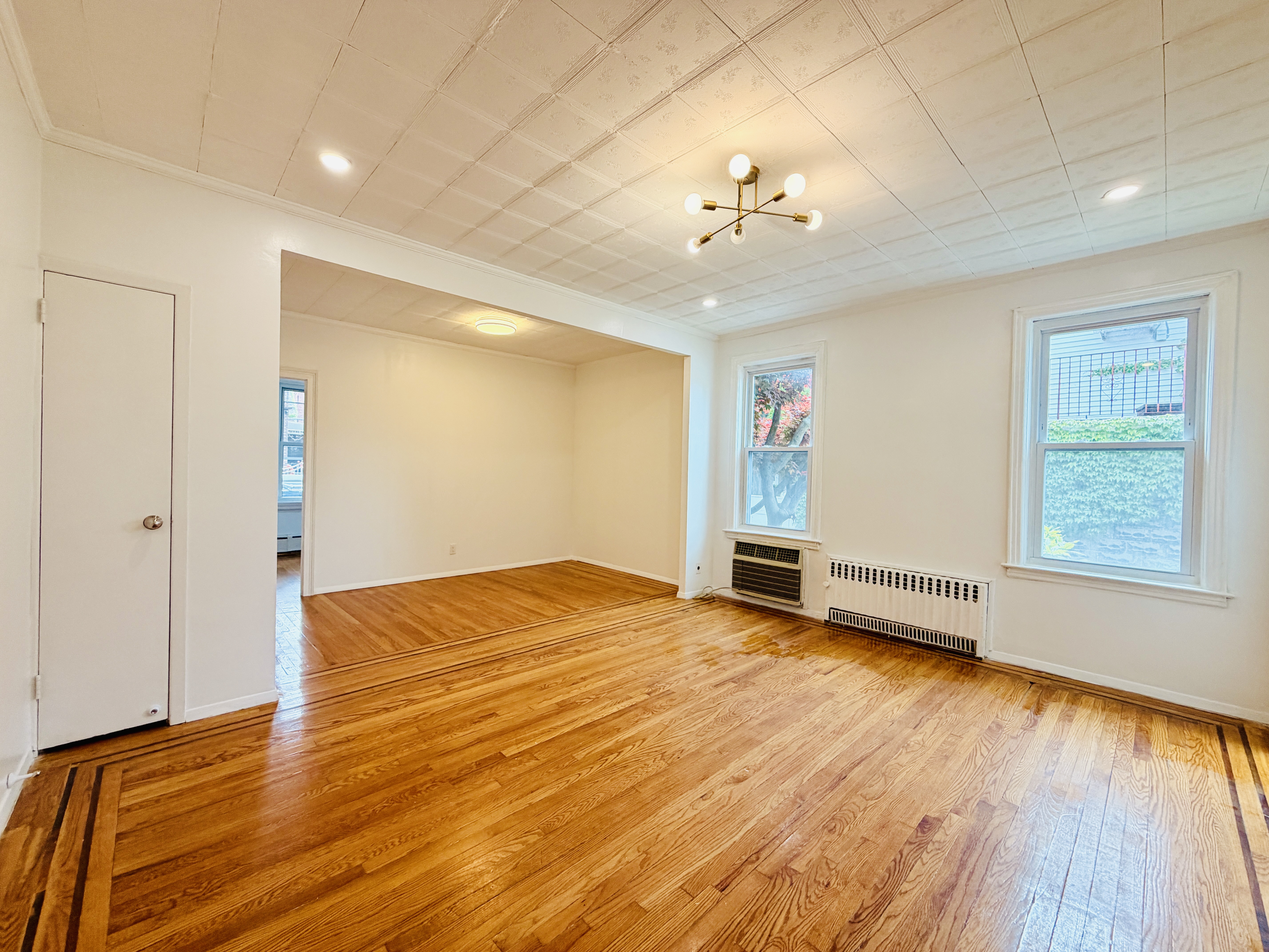 63-33 Haring Street, Unit 1F Queens, NY 11374 - Photo 2 of 13 wooden floor in an empty room with a window
