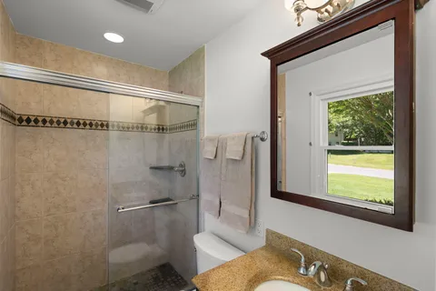 a bathroom with a granite countertop sink toilet and shower