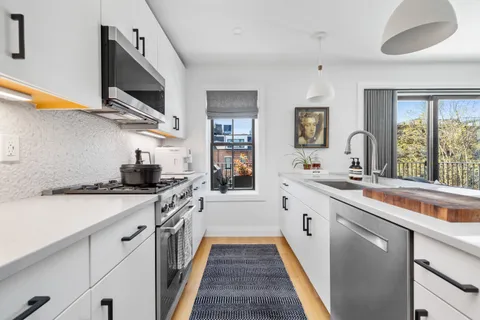a kitchen with stainless steel appliances granite countertop a sink and a stove next to a window