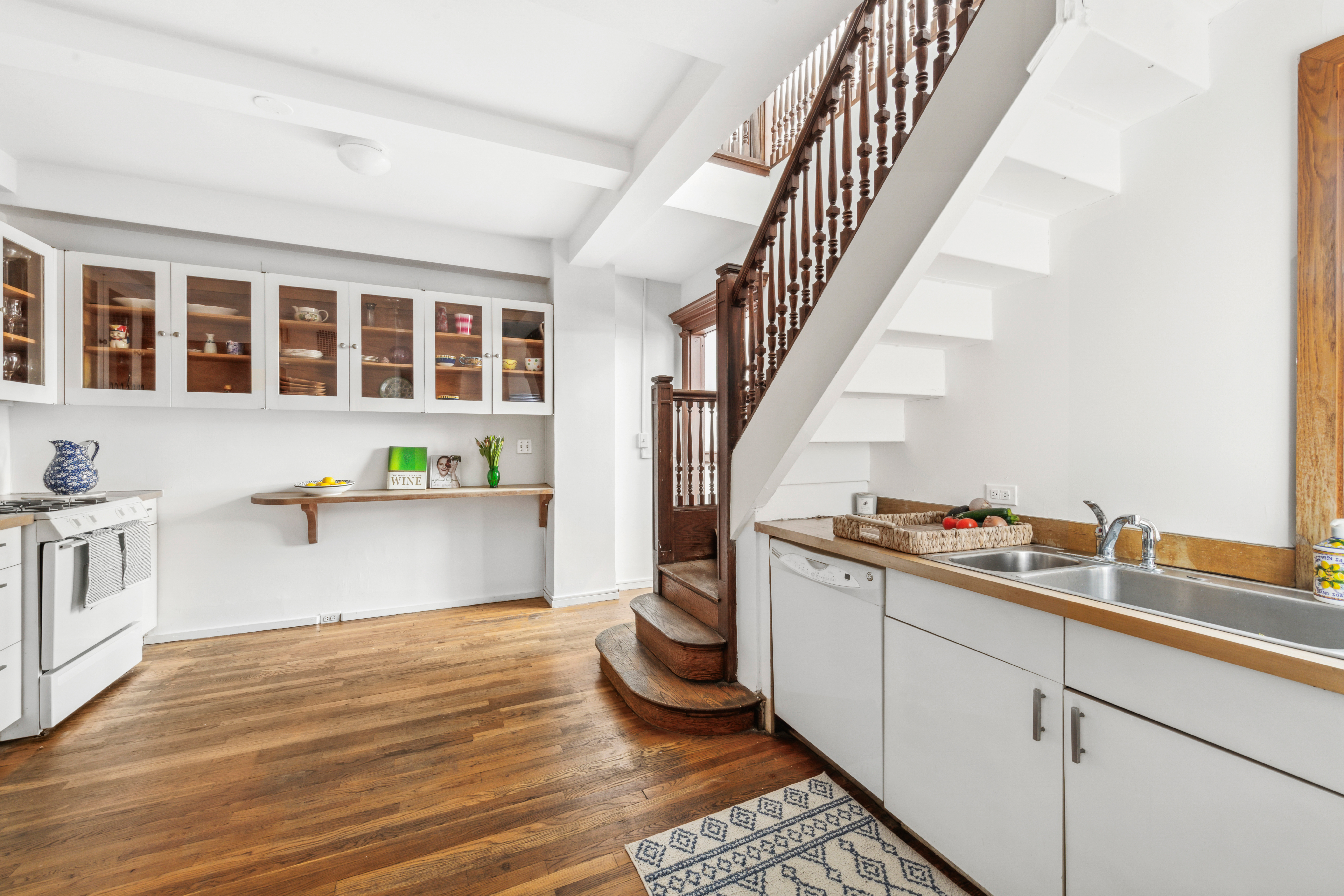 1 West 67th Street, Unit 501/502 Manhattan, NY 10023 - Photo 8 of 19 a kitchen with a sink and white cabinets with wooden floor