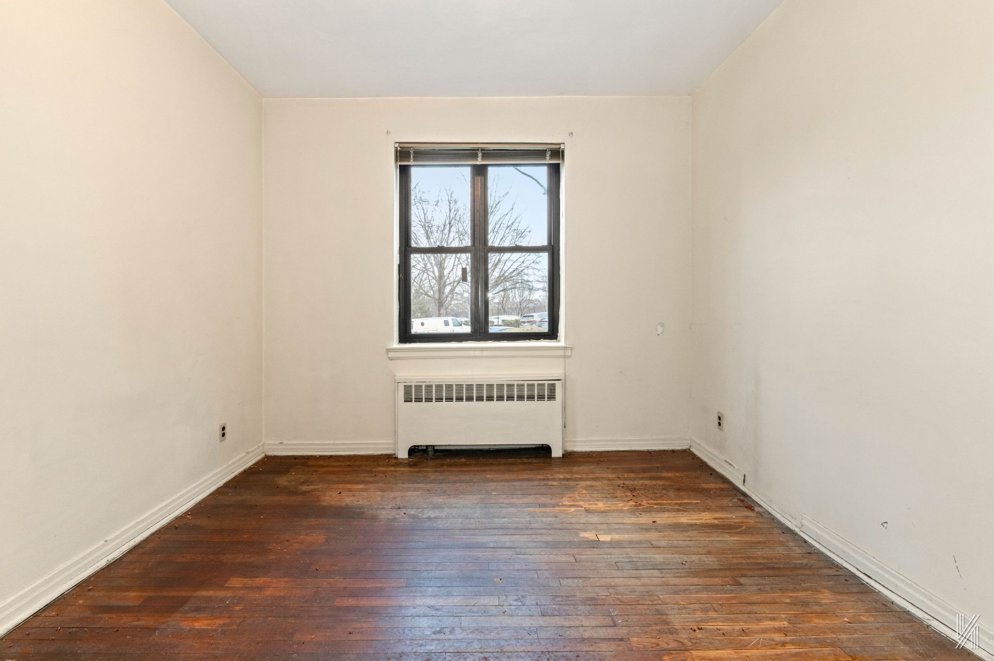 22-60 79th Street, Unit 1A Queens, NY 11370 - Photo 12 of 17 an empty room with wooden floor and windows