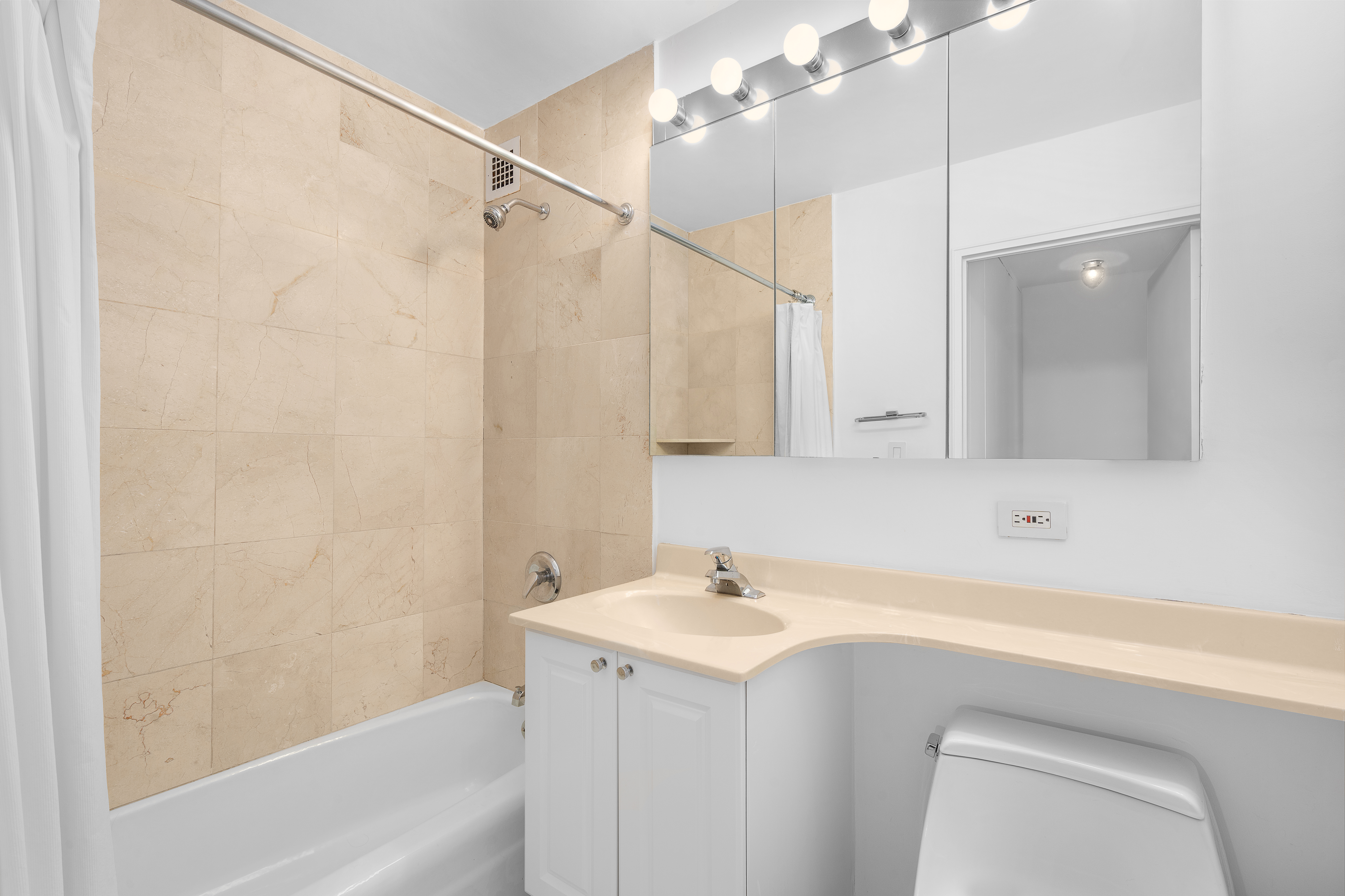 301 East 79th Street, Unit 18C Manhattan, NY 10075 - Photo 5 of 13 a bathroom with a sink a mirror and a bathtub