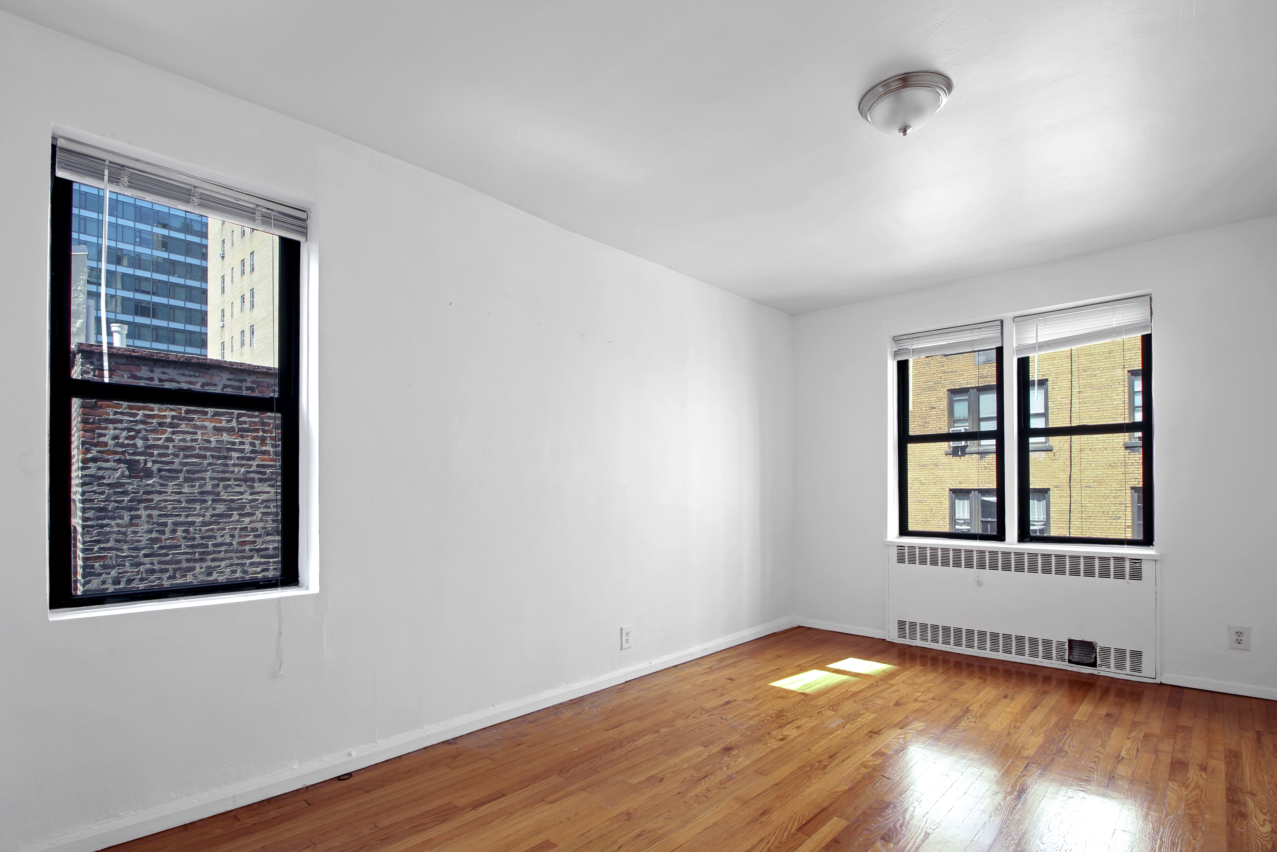 315 East 56th Street, Unit 6C Manhattan, NY 10022 - Photo 3 of 5 an empty room with wooden floor and windows