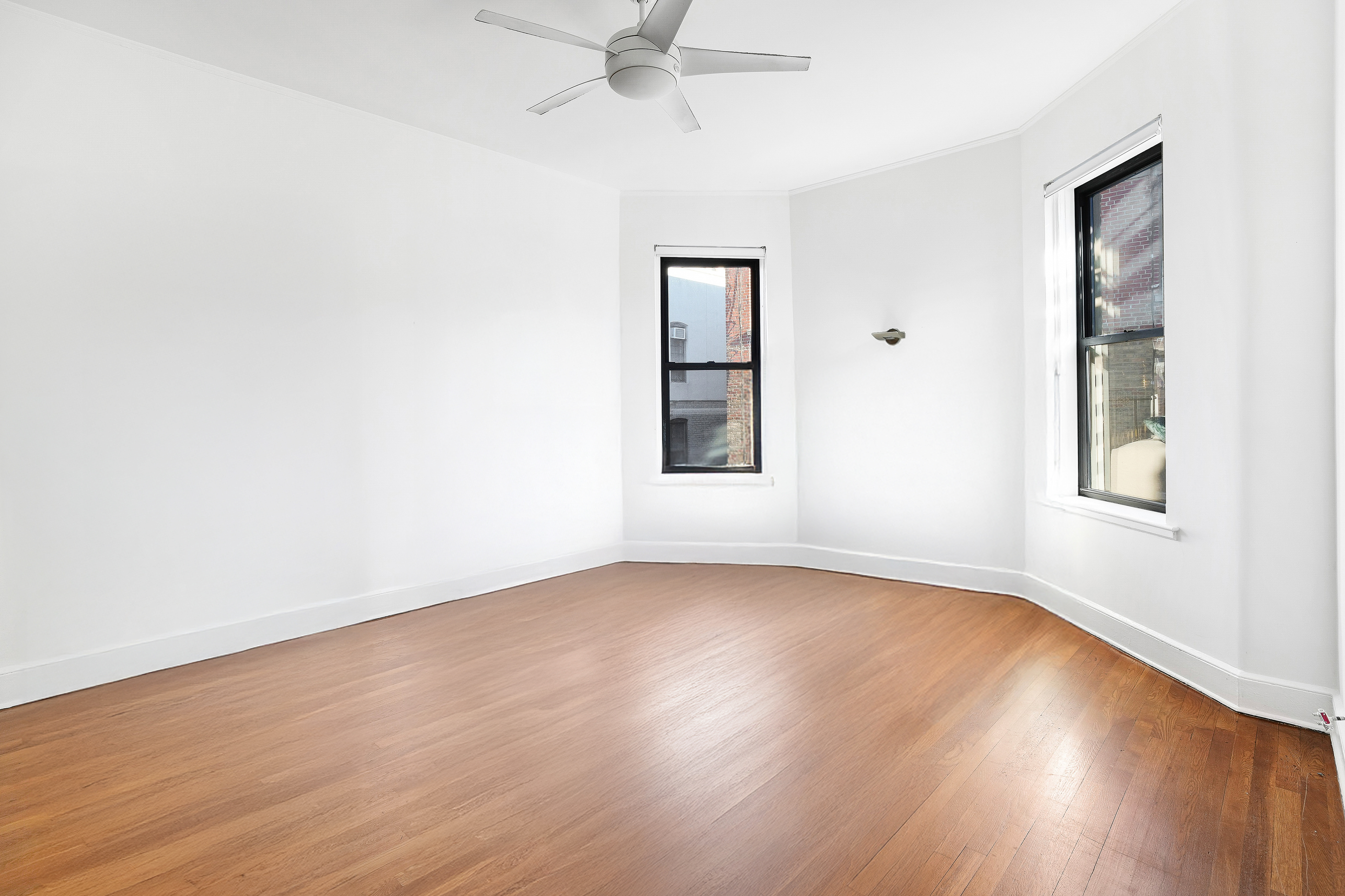 215 West 105th Street, Unit 5DPH Manhattan, NY 10025 - Photo 7 of 16 an empty room with wooden floor chandelier fan and windows