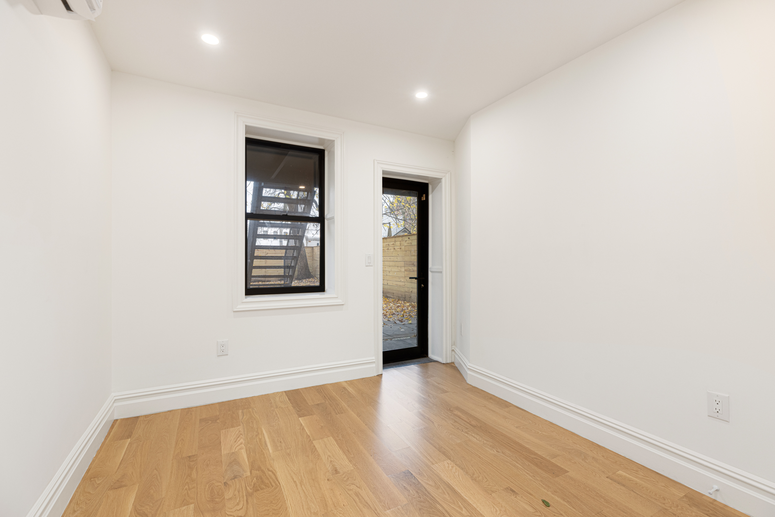 15 Verona Place, Unit GARDEN Brooklyn, NY 11216 - Photo 5 of 14 an empty room with wooden floor and windows
